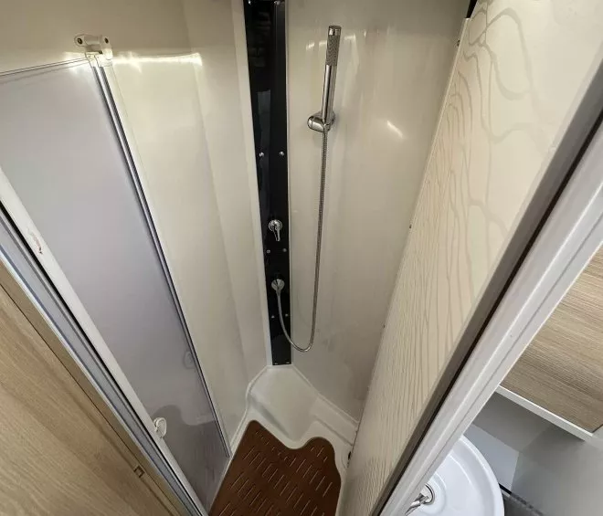 Douche compacte avec paroi en bois et lavabo intégré dans un espace réduit.