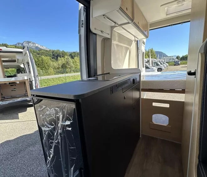 Intérieur d'un van aménagé avec vue sur l'extérieur et rangements intégrés