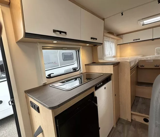 Intérieur d'un camping-car moderne avec cuisine équipée et espace de couchage.