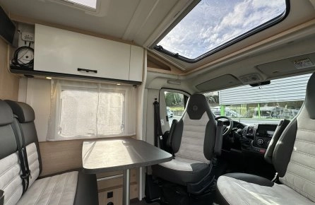 Intérieur d'un camping-car moderne avec sièges et table.