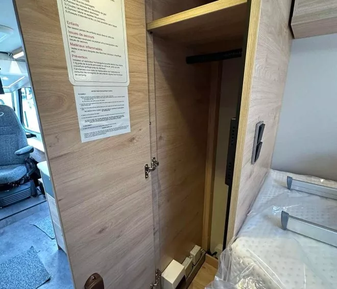 Intérieur d'un placard en bois avec consignes de sécurité dans un camping-car moderne.