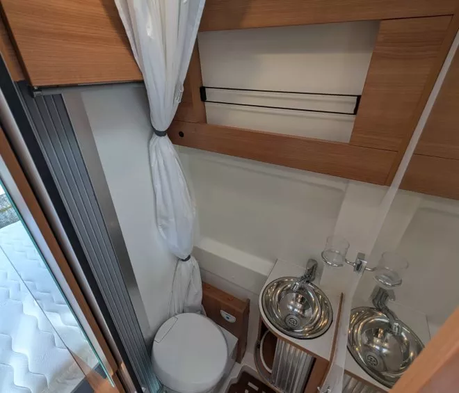 Salle de bain compacte dans un camping-car avec toilettes et lavabo en acier inoxydable