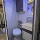Salle de bain compacte dans un camping-car avec toilettes et lavabo modernes.