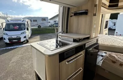 Intérieur d'un camping-car moderne avec cuisine équipée et espace de couchage.