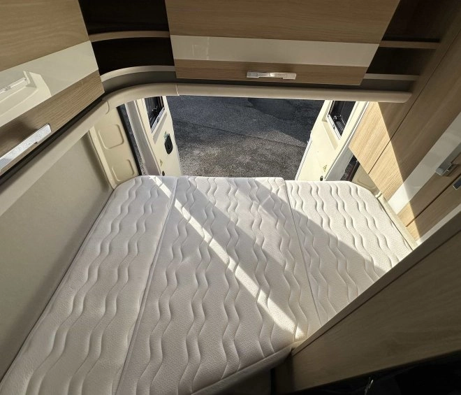 Intérieur d'un camping-car avec lit pliant et rangements en bois clair