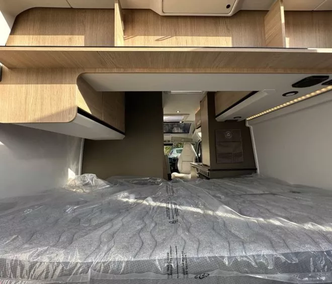 Intérieur d'un camping-car avec lit et rangements en bois clair