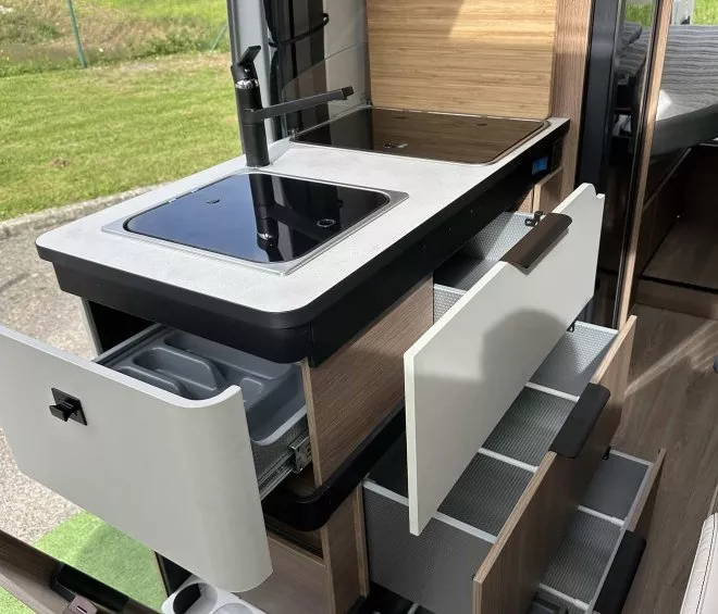 Cuisine compacte de camping-car avec évier, plaques de cuisson et rangements ouverts