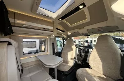 Intérieur d'un camping-car moderne avec sièges et table, vue sur le toit ouvrant.