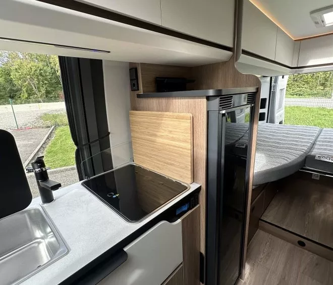 Intérieur moderne d'un camping-car avec cuisine équipée et lit.
