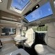 Intérieur d'un camping-car moderne avec sièges en cuir et toit panoramique.