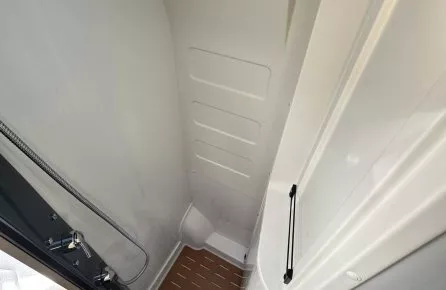 Douche compacte avec sol en bois dans un camping-car moderne.