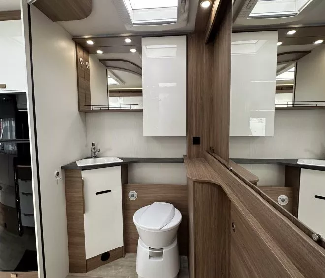 Salle de bain moderne dans un camping-car avec toilettes et lavabo intégrés.