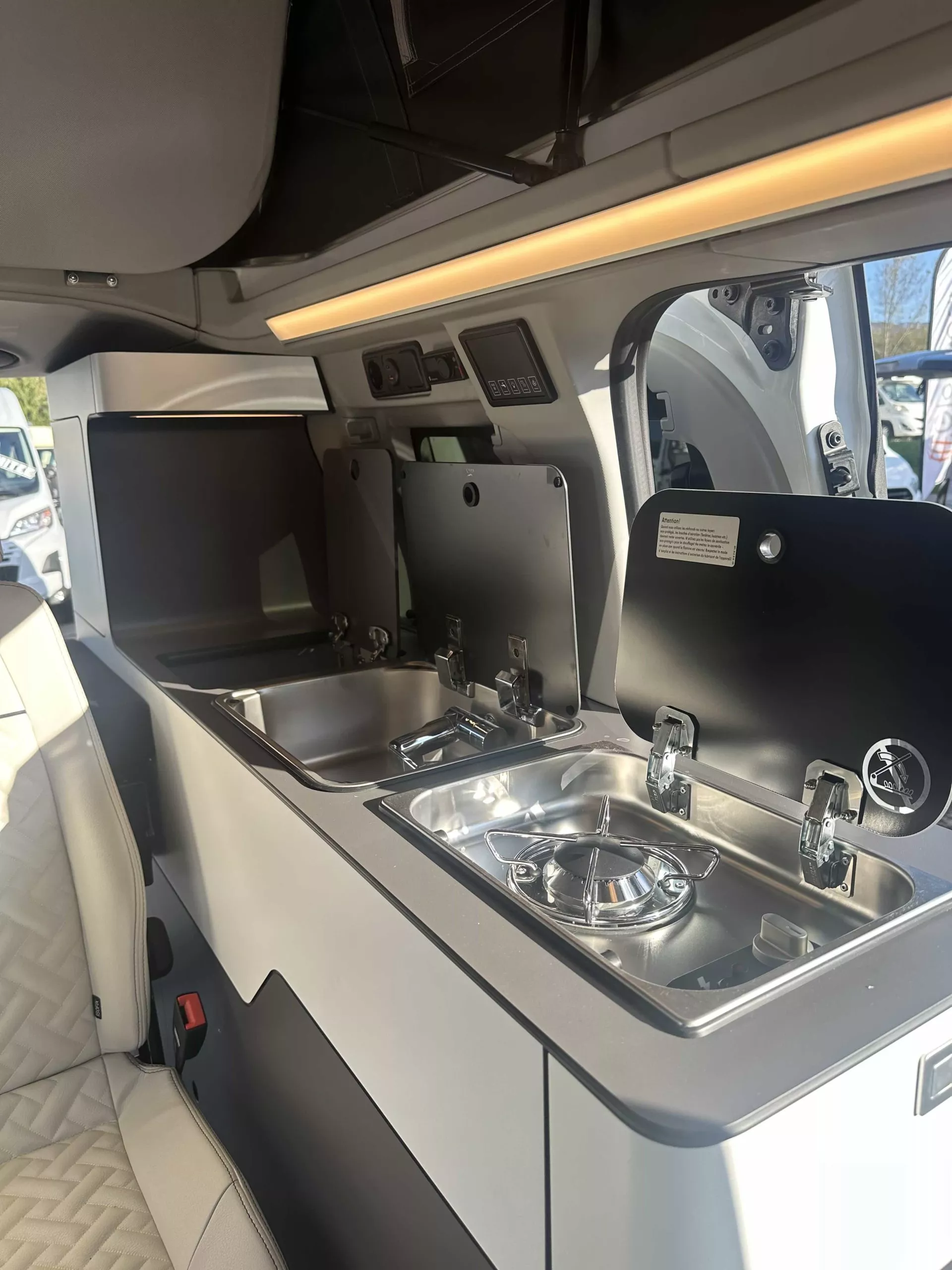 Cuisine intégrée dans un van aménagé avec évier et réchaud.