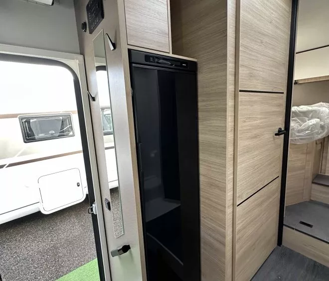 Intérieur d'un camping-car moderne avec placards en bois clair et réfrigérateur intégré.
