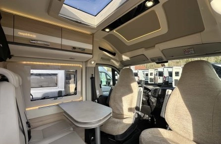 Intérieur d'un camping-car moderne avec sièges et table, vue sur le toit ouvrant.