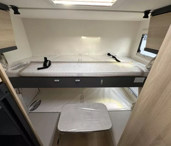 Intérieur d'un camping-car avec lit superposé et rangements en bois clair.