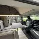 Intérieur d'un van aménagé avec sièges et table pliante, vue sur l'extérieur