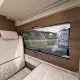 Intérieur d'un camping-car avec siège beige et fenêtre panoramique.