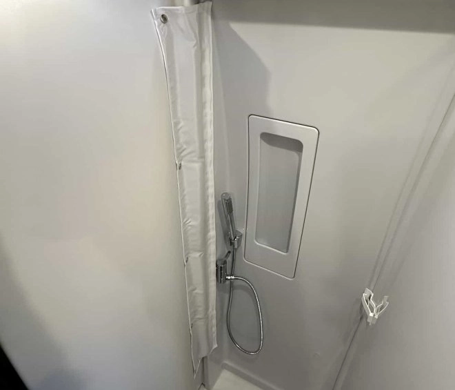 Douche compacte avec pommeau et rideau dans un espace restreint