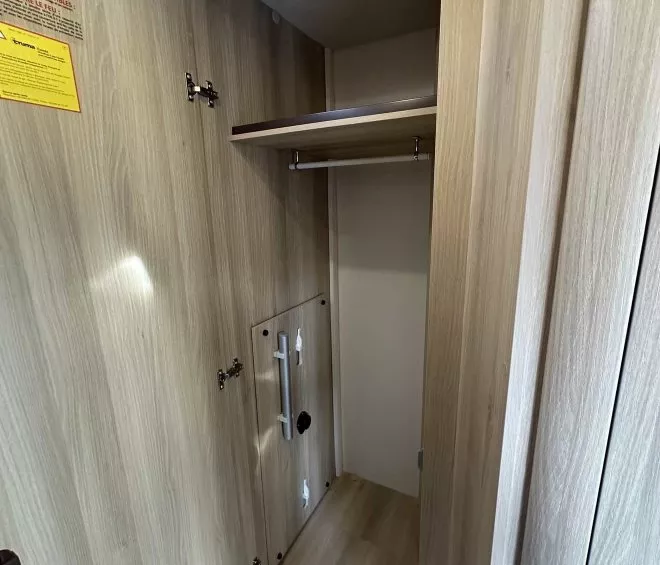 Placard en bois clair avec étagère et tringle, intérieur de camping-car.