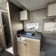 Cuisine compacte de caravane avec évier, plaque de cuisson et rangements en bois clair.