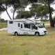 Camping-car stationné dans un champ entouré d'arbres