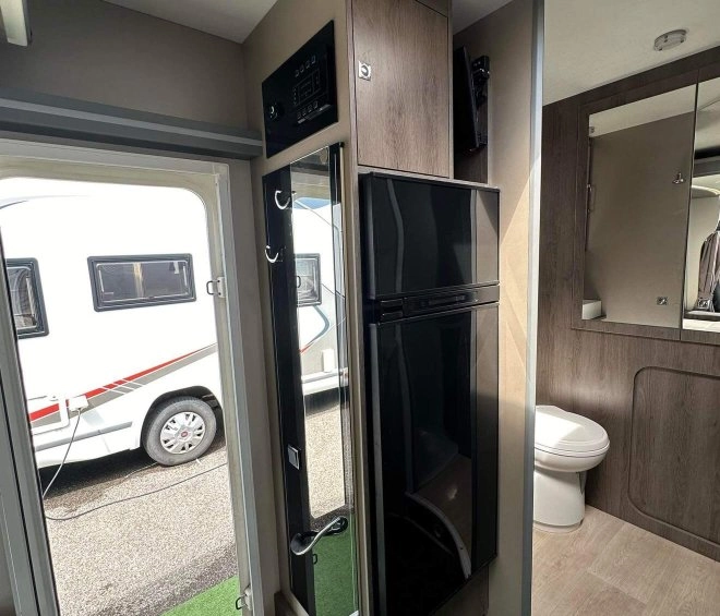 Intérieur d'une caravane moderne avec salle de bain et réfrigérateur visible.