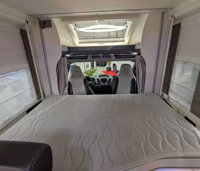 Intérieur d'un camping-car avec lit escamotable et sièges avant visibles