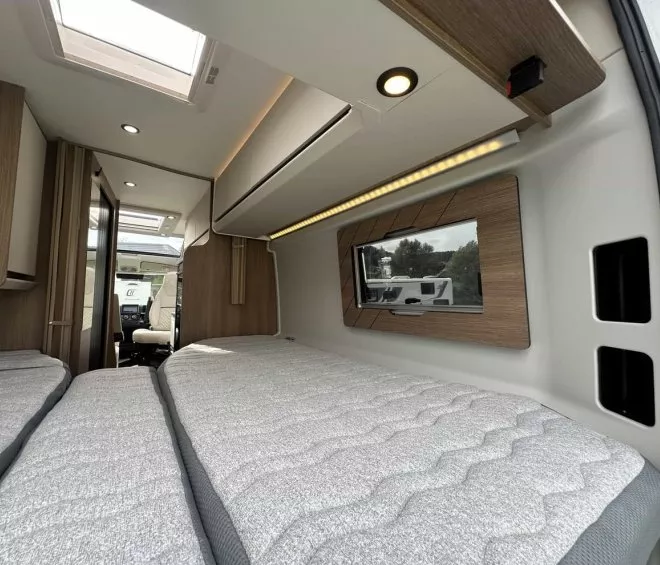 Intérieur d'un camping-car moderne avec lits jumeaux et éclairage intégré.