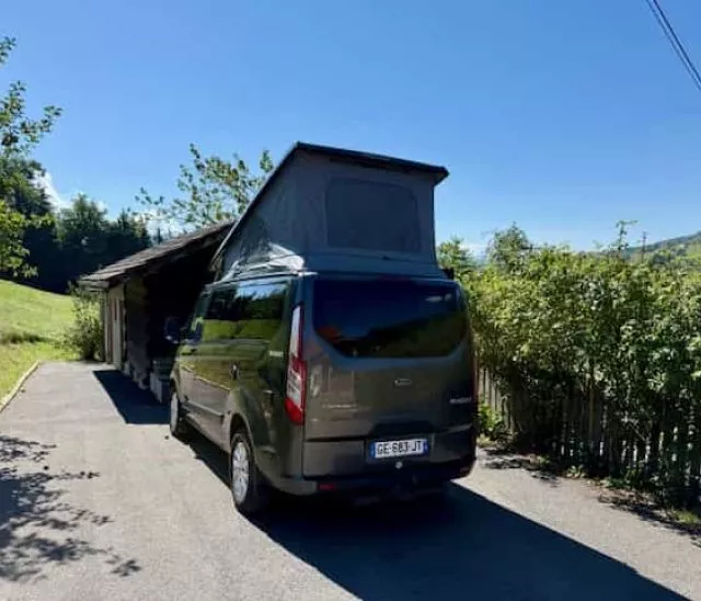 Van aménagé stationné près d'un abri en bois dans un cadre rural