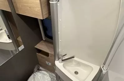 Salle de bain compacte avec lavabo, toilettes et douche dans un camping-car moderne.