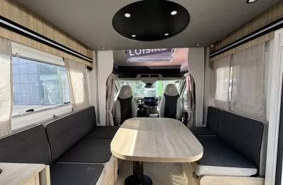 Intérieur spacieux d'un camping-car moderne avec table et banquettes grises