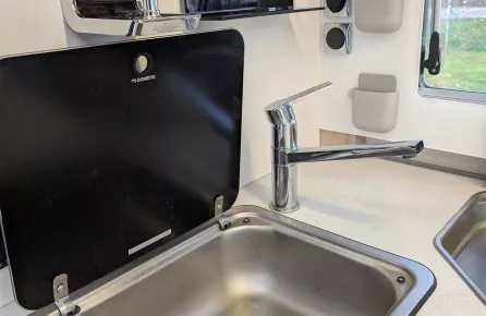 Évier en acier inoxydable avec robinet moderne dans une cuisine compacte de camping-car.