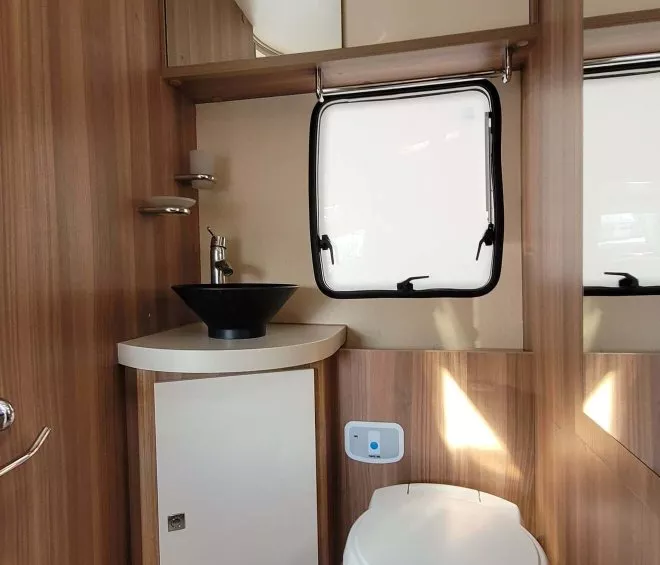 Salle de bain compacte en bois avec lavabo et toilettes dans un camping-car.