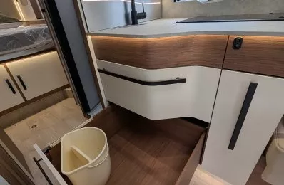 Cuisine moderne de camping-car avec évier, tiroir ouvert et poubelle intégrée