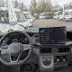 Intérieur d'un véhicule Volkswagen avec écran de contrôle, vue sur camping-cars en arrière-plan.