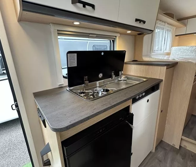 Cuisine compacte de camping-car avec évier, réfrigérateur et rangements.