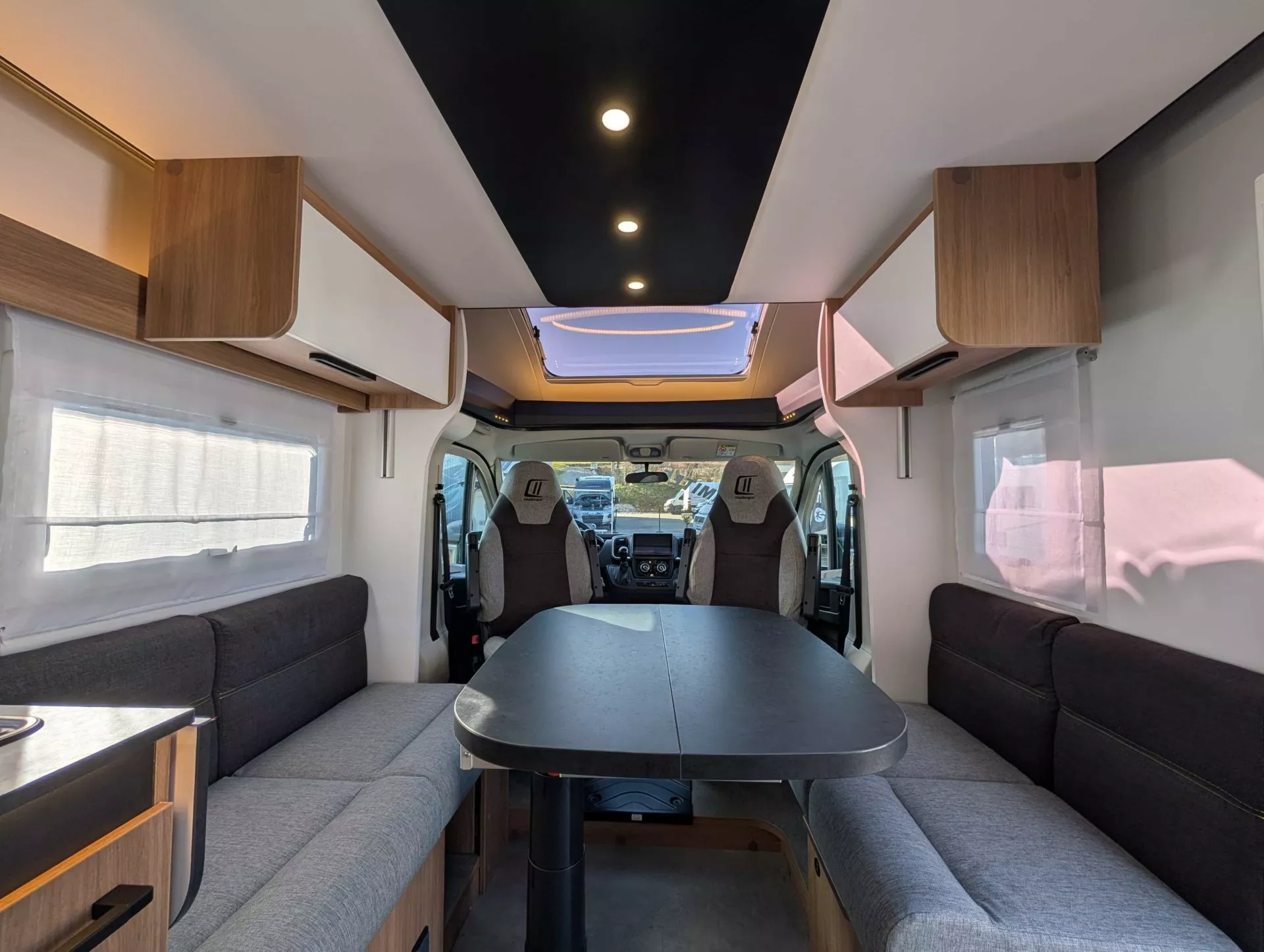 Intérieur spacieux d'un camping-car moderne avec table et banquettes grises