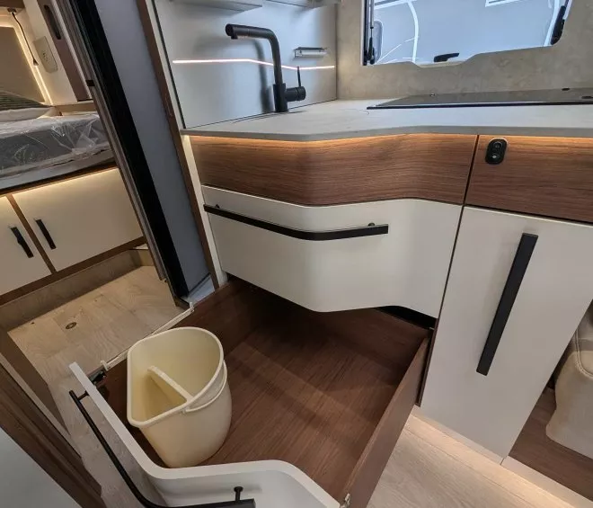 Cuisine moderne de camping-car avec évier, tiroir ouvert et poubelle intégrée