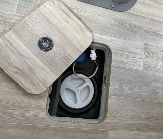 Trappe de sol ouverte révélant un réservoir encastré dans un plancher en bois clair