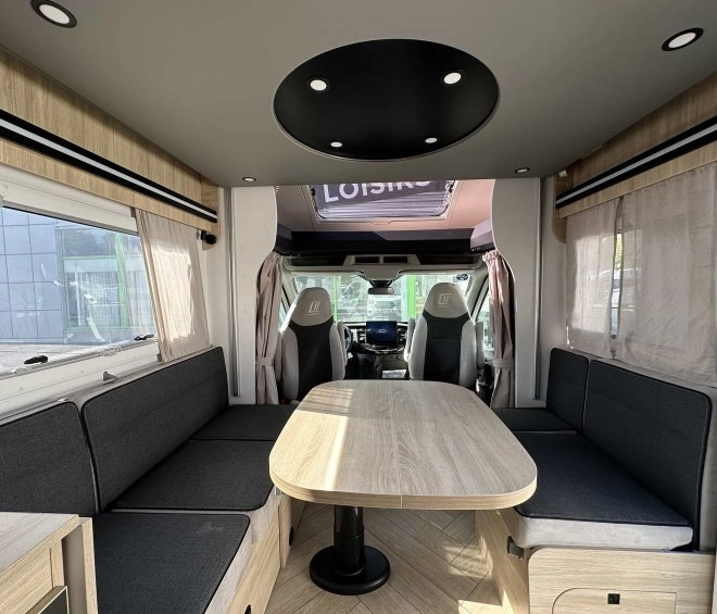 Intérieur spacieux d'un camping-car moderne avec table et banquettes grises