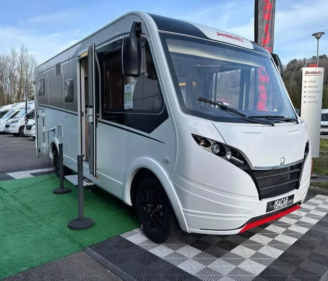 Camping-car Dethleffs blanc exposé sur un parking avec d'autres véhicules similaires.