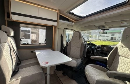 Intérieur d'un camping-car moderne avec sièges et table, éclairage naturel.