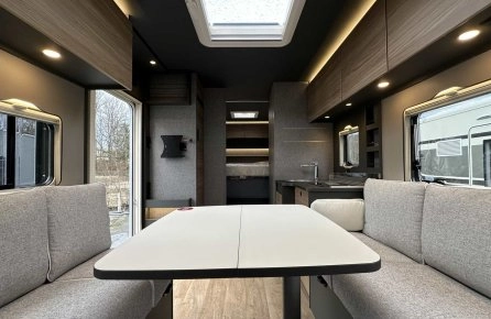 Intérieur moderne d'un camping-car avec table et banquettes grises