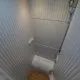 Douche compacte avec parois blanches et caillebotis en bois, éclairage intégré.