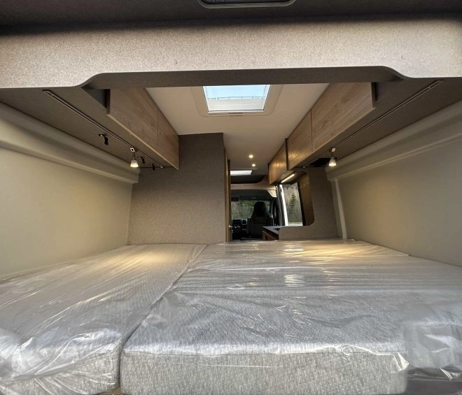 Intérieur d'un van aménagé avec lit double et rangements en bois clair