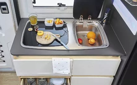 Cuisine compacte de camping-car avec évier, planche à découper et fruits