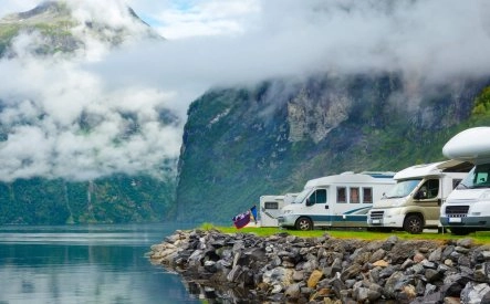 Camping-cars stationnés au bord d'un fjord norvégien avec montagnes et nuages