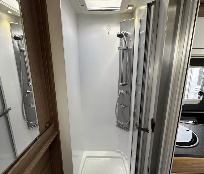 Douche moderne avec parois vitrées et puits de lumière dans un camping-car.