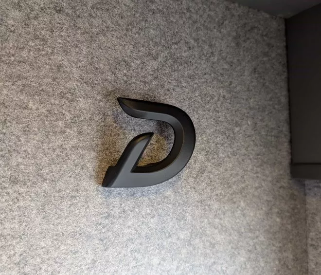 Logo noir stylisé sur mur gris texturé